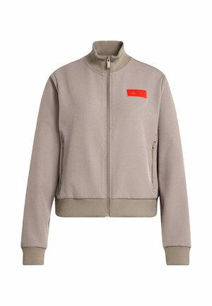 Beige Reißverschlussjacke mit gerippten Bündchen und Saum, hohem Kragen, seitlichen Reißverschlusstaschen und kleinem roten Logo-Patch auf der linken Brust.