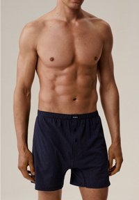 Granatowe bokserki w kropki, z elastycznym pasem i guzikiem z przodu. Wykonane z lekkiego, oddychającego materiału.