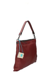 Sac à bandoulière en cuir rouge avec une surface texturée, fermeture zippée sur le dessus et une courte anse. Comprend une étiquette de couleur crème avec des accents bleus.