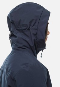 Veste navale résistante aux intempéries avec capuche, dotée d'ajustements à cordon, d'une texture lisse et d'une silhouette ajustée.