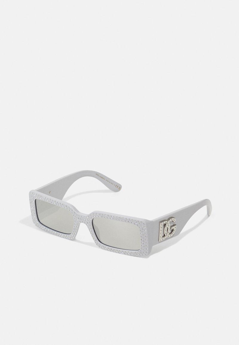 Lunettes de soleil grises avec des verres rectangulaires, rehaussées de strass sur la monture et d'un logo argenté sur un côté.