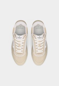 Paire de baskets Copenhagen Studios beige et blanche avec lacets, vue de dessus sur un fond blanc uni.