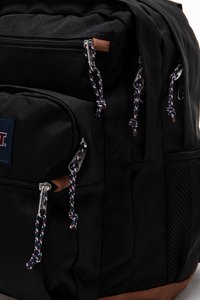 Sac à dos noir en tissu durable, doté de plusieurs poches zippées, de quincaillerie argentée et de cordons de tirage à motifs en rouge, blanc et bleu.