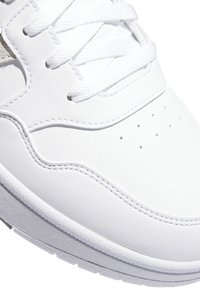 Sneaker bianco in pelle con texture liscia, dotato di lacci tondi e perforazioni sull'area delle dita. Accentuato da una suola in gomma bianca.