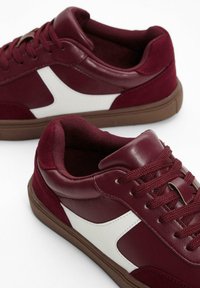 Burgunderfarbene Sneakers aus Leder und Wildleder, mit weißen Akzenten, runder Zehenpartie, strukturierten Sohlen und flachen Schnürsenkeln.