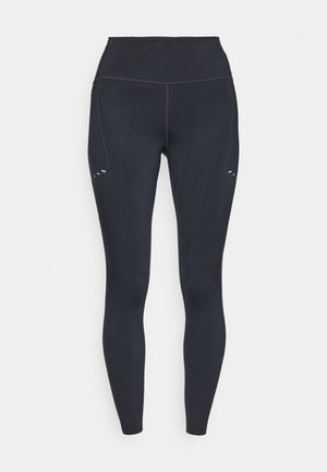 Leggings noirs avec une taille haute, fabriquées dans un matériau extensible, présentant des détails de couture subtils et de petites découpes sur la cuisse supérieure.