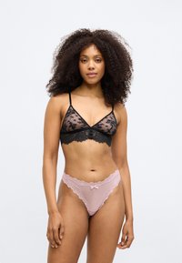 Črna čipkasta bralette z triangularnimi skodelicami in tankimi naramnicami, v kombinaciji z roza čipkastim tangicami z majhno pentljo spredaj.