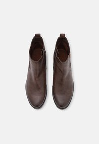 Stivali ankle in pelle marrone con punta tonda, texture liscia, zip laterale e linguetta sul retro. Design minimalista, senza motivi visibili.