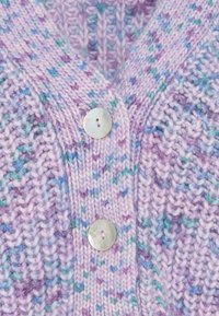 Gebreid lavendelvest met gespetterde blauwe en paarse accenten. Voorzien van een V-hals en drie grote ronde knopen van parelmoer aan de voorkant.