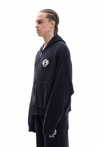 Black zip-up hoodie with a textured waffle knit design, featuring a front pocket and an embroidered logo on the chest and sleeve.