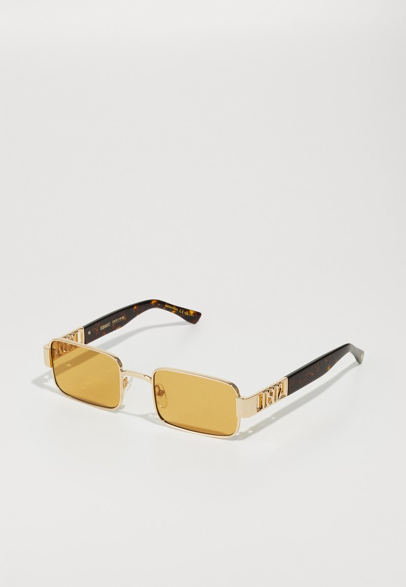 Ochelari de soare rectangulari cu nuanță galbenă, cu rame din metal aurit și brațe cu model țestoasă, având un accent de marcă pe laterale.