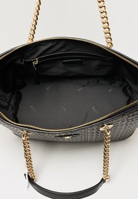 Borsa a tracolla in pelle nera con motivo a rilievo, dettagli in catena dorata, chiusura con zip e interno in tessuto nero con stampa del logo e tasca con zip.