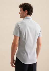 Camicia grigio chiaro a maniche corte con colletto, texture liscia e dettagli costruttivi sottili sulla schiena.