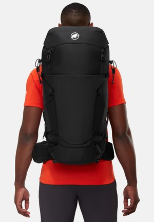 Schwarzer Outdoor-Rucksack mit verstellbaren Trägern, mehreren Fächern und einer runden Oberseite. Texturiertes Material mit Logo-Detail oben.