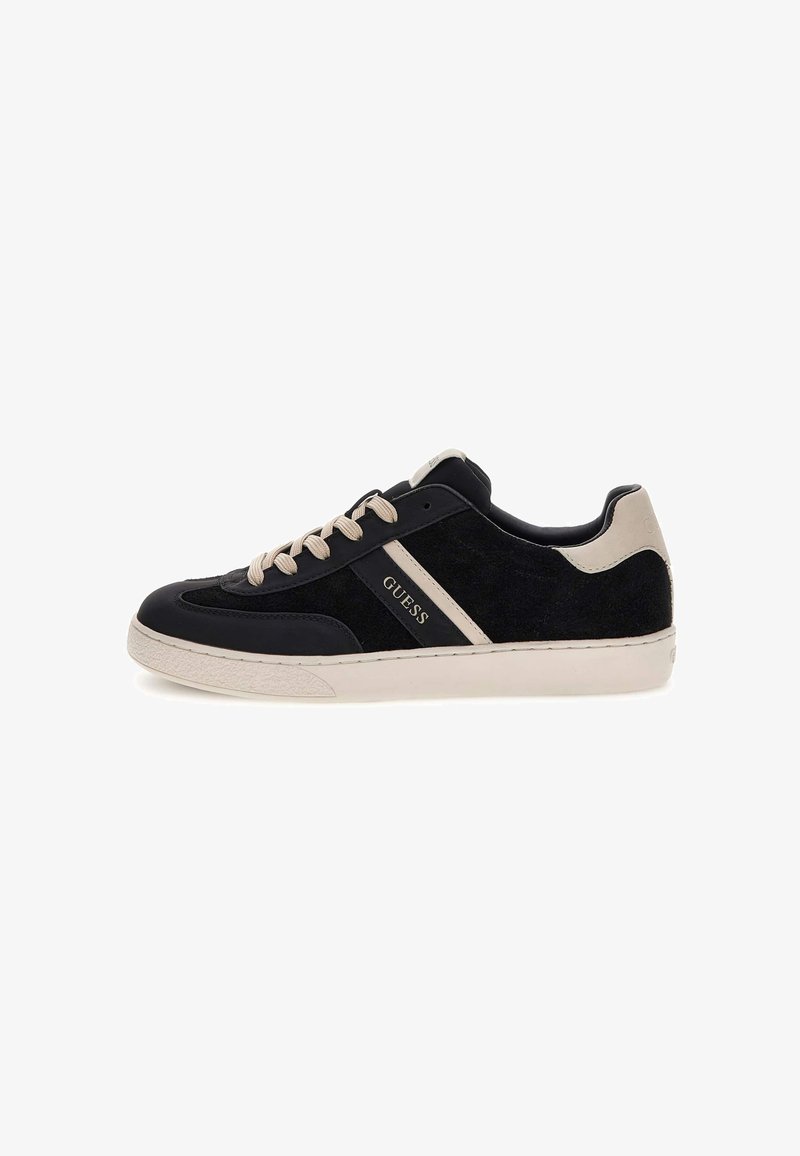 Schwarze Wildleder- und Leder-Sneaker mit beigen Akzenten, runder Zehenpartie, Schnürverschluss und sichtbarem Logo. Abgerundete Sohle mit strukturiertem Profil.