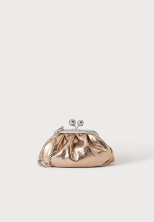Petit sac pochette métallique dorée avec fermoir argenté et chaîne sur un fond clair uni.