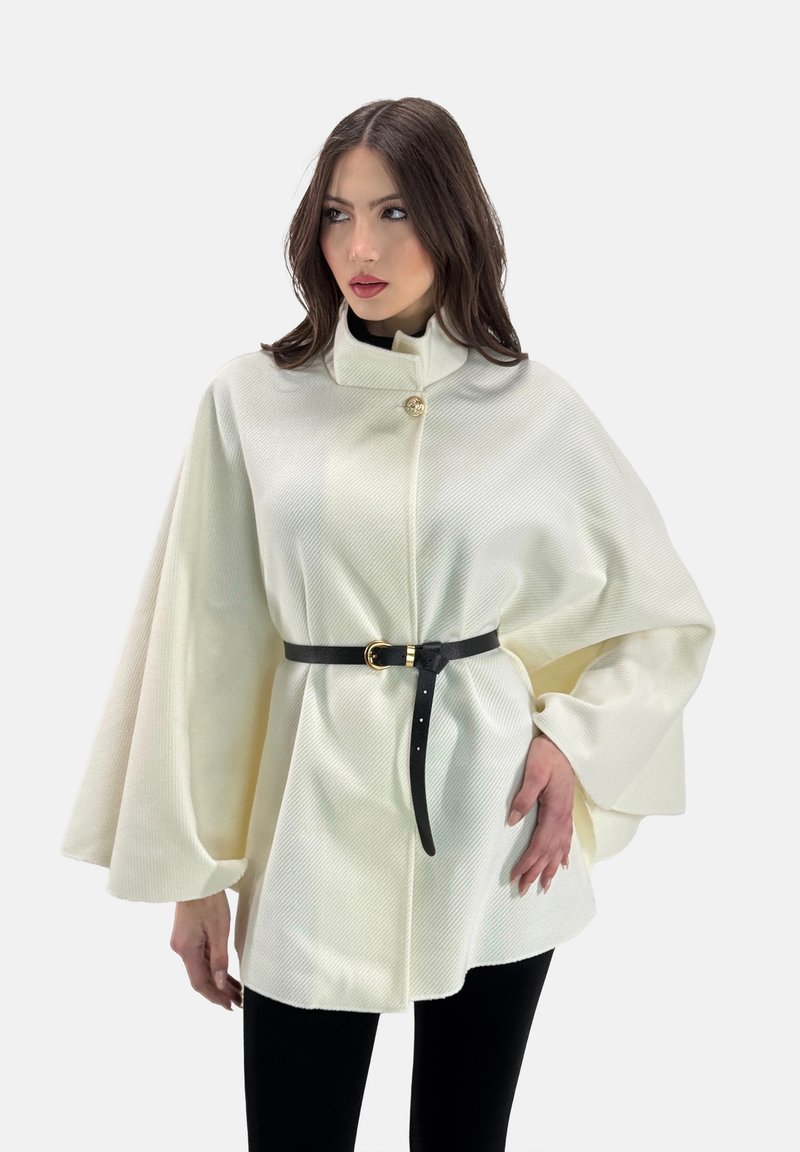 Capa blanca texturizada con mangas de gran tamaño, cuenta con un alto cuello, botón dorado y un cinturón negro en la cintura.