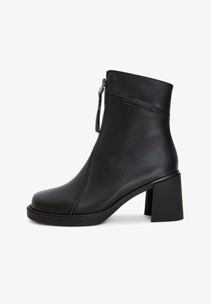 Schwarze Leder-Ankle-Boots mit rechteckiger Zehenform, einem seitlichen Reißverschluss und einem stabilen Blockabsatz. Glatte Textur und minimalistisches Design.