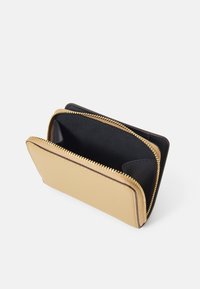 Portafoglio zip compatto in materiale testurizzato beige con interno nero. Presenta una cerniera in tono oro e un compartimento aperto per carte o contanti.