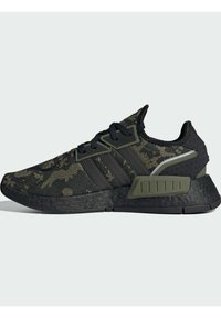 Sorte og grønne camouflage sneakers med en tekstureret strikoverdel, forstærkede sider og tre sorte striber. Gummisål med accentdetaljer.