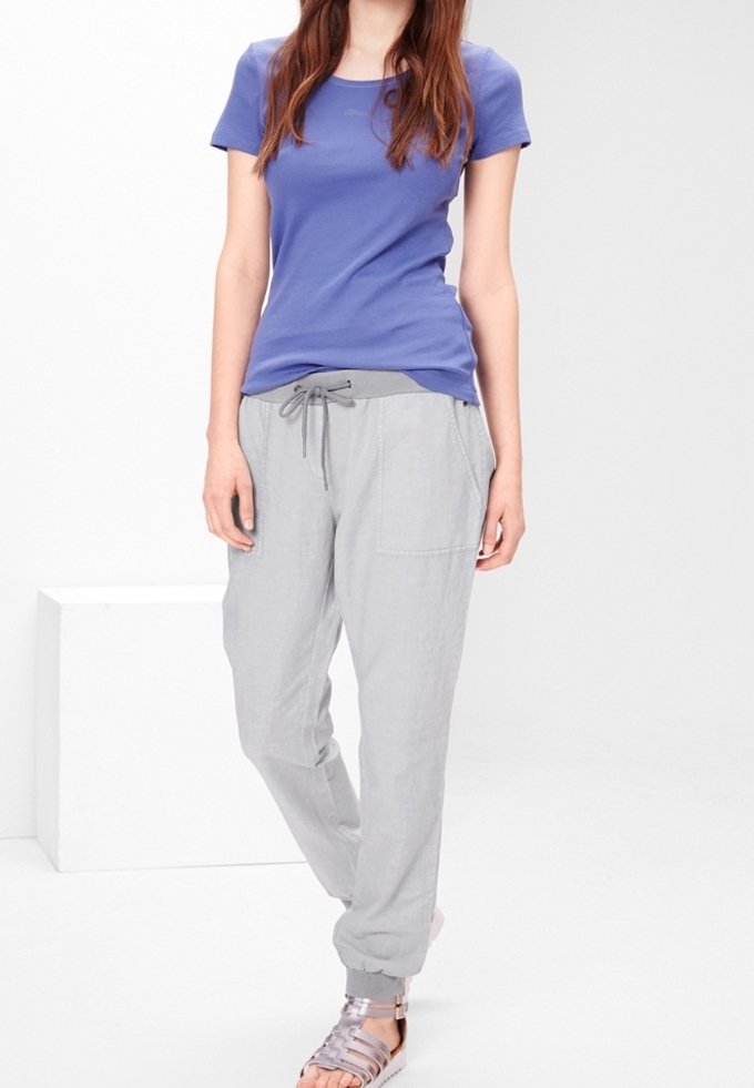 Chemise à manches courtes violette, pantalon gris clair à cordon de serrage avec poches, et sandales métalliques. Tissu léger, coupe décontractée et design relaxé.