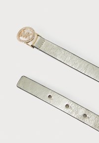 Metallisk sølvbelte med teksturert overflate, som har en sirkulær gullspenne dekorert med klare rhinestones og med en svart kantdetalj.