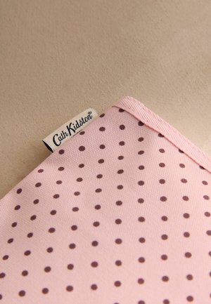 Vaaleanpunainen kangas, jossa on ruskeita pilkkuja, ja ommeltu valkoinen etiketti, jossa lukee "Cath Kidston"-merkin nimi.