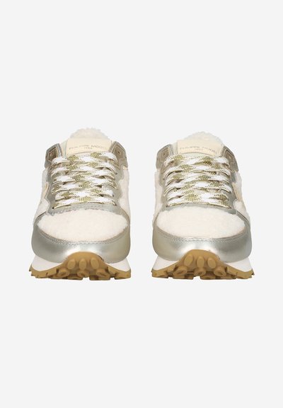 White and gold sneakers with a textured, fuzzy upper, metallic accents, and thick rubber soles featuring a gripped tread.