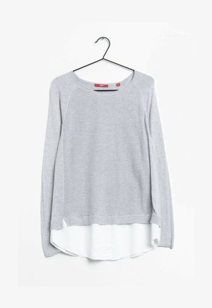 Pull en tricot gris avec une coupe décontractée, doté d'un ourlet de chemise blanche en superposition et d'un large décolleté. Les manches sont longues avec des poignets côtelés.