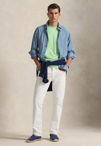 Γαλάζιο τζιν πουκάμισο πάνω από πράσινο μπλουζάκι, λευκό τζιν παντελόνι και μπλε εσπαντρίγιες. Σκούρα μπλε πουλόβερ δεμένο γύρω από τη μέση. Απλή, καθημερινή στολή.