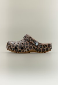 Καφέ clog τύπου slip-on με μαύρα λεοπάρ στίγματα, οπές αερισμού και ρυθμιζόμενο λουράκι στη φτέρνα με κυκλικό λογότυπο.