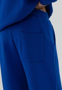 Koningsblauwe joggingbroek met een elastische tailleband en een achterzak met subtiele stikseldetails. Gemaakt van een gladde katoenmix.