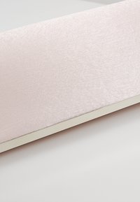 Gros plan d'un panneau rectangulaire avec un tissu texturé rose clair et une fine bordure beige sur fond blanc.