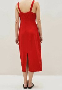 Rotes Midi-Kleid mit breiten Trägern, tailliertem Oberteil und einem Reißverschluss in der Mitte des Rückens. Verfügt über einen subtilen Schlitz am Rücken. Glattes, weiches Material.