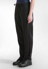 Pantaloni jogger neri, morbidi e comodi, con cintura elastica e cordoncino. Realizzati in tessuto liscio, dotati di tasche laterali e gamba dritta.