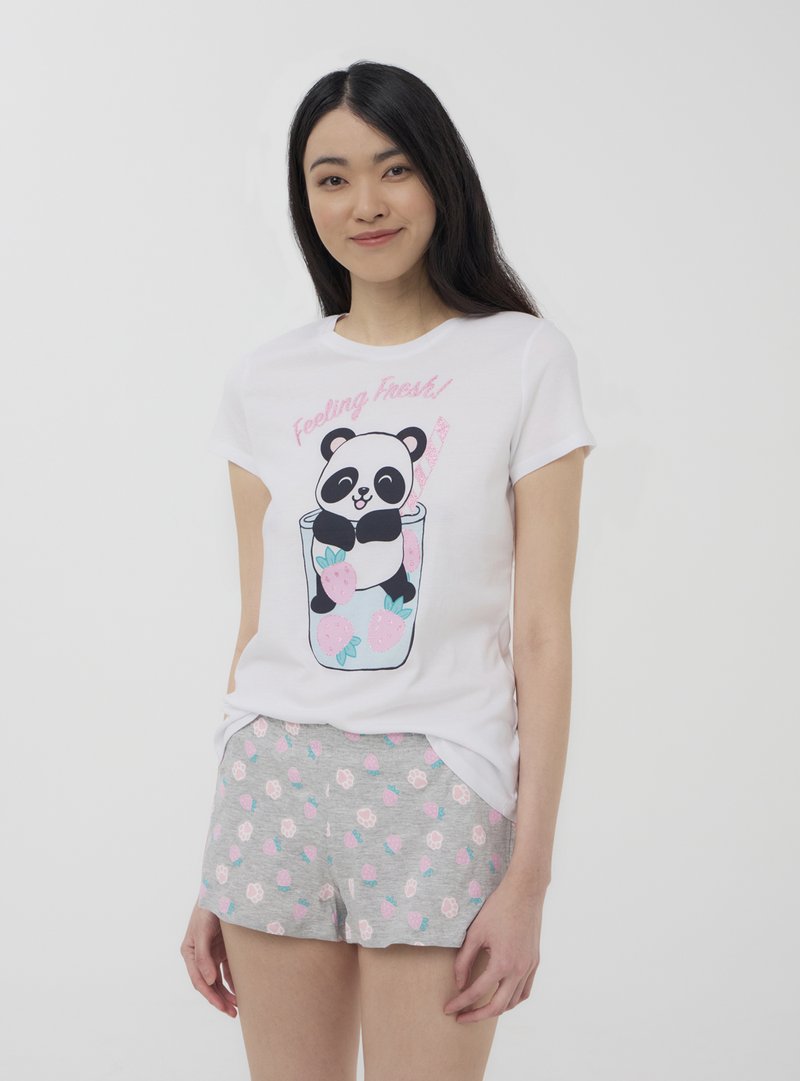 T-shirt bianca in cotone con una grafica di un panda in un bicchiere, abbinata a pantaloni corti grigi con motivi di fragole rosa e fiori.