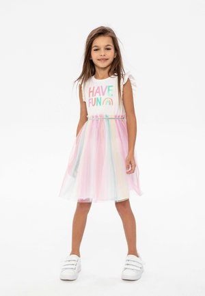 T-shirt blanc avec un texte coloré "HAVE FUN", associé à une jupe en tulle multicolore. Tissu lumineux et léger avec une texture douce.