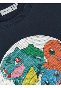 Sudadera de color navy con un gráfico circular texturizado que presenta personajes de dibujos animados coloridos: verde, naranja, azul y amarillo, todos con expresiones faciales prominentes.