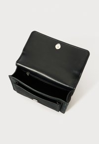Billetera de cuero negro con una textura suave, cierre a presión y dos compartimentos, uno con un bolsillo con cremallera, presentando acentos de hardware plateado.