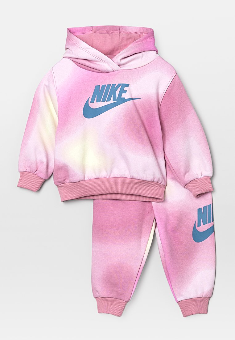 Ensemble de hoodie et de pantalons de survêtement Nike en dégradé rose avec un logo bleu, présenté sur un fond gris clair.