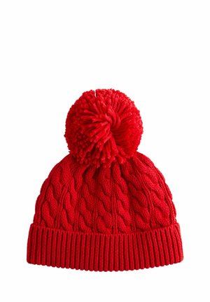 Bonnet tricoté rouge avec un motif en câble, doté d'un grand pompon sur le dessus et d'un bord côtelé à la base. Texture douce tout au long.