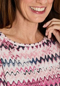 Kurzarmoberteil in Rosa und Creme mit einem wellenförmigen, abstrakten Muster, das einen weiten Halsausschnitt und einen weichen, strukturierten Stoff aufweist.
