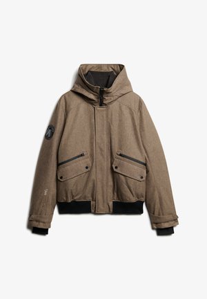 Veste marron à motifs avec capuche. Comprend des poches zippées, un bord noir en bas et un écusson avec logo sur la manche.