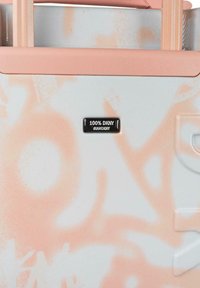 Maleta blanca con patrones de coral abstractos, superficie texturizada y una etiqueta negra con la inscripción "100% DKNY #IAMDKNY" en la parte frontal.