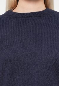 Pulover tricotat de culoare bleumarin, cu un model țesut în relief și guler rotund. Material moale, cu o siluetă ajustată.