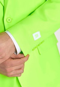 Neon-grüner Anzugjackenärmel aus glattem Stoff mit vier passenden Knopfakzenten und einem weißen Etikett mit der Aufschrift "GOPRO SUITS".