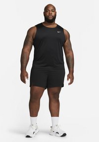 Musthave musta sportlik tank top ja lühikesed püksid, millel on ümmargune kaelus, kerge kangas ja peegeldav logo, kombineeritud valgete tossude ja sokkidega.