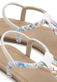 Braided multicolored straps in light pastel tones over a beige sole, featuring a smooth texture and minimalistic white accents.