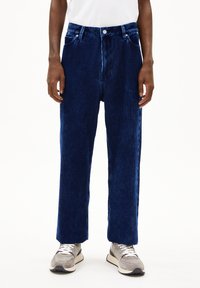 Navyblauwe corduroy broek met een rechte snit, voorzien van voorzakken, riemlussen en een gestructureerd oppervlak. Gecoördineerd met grijze sneakers.