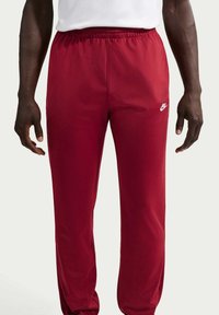 Κόκκινο αθλητικό παντελόνι από λείο, ελαστικό ύφασμα με ελαστική μέση. Διαθέτει λευκό λογότυπο Nike στο αριστερό μπούτι.